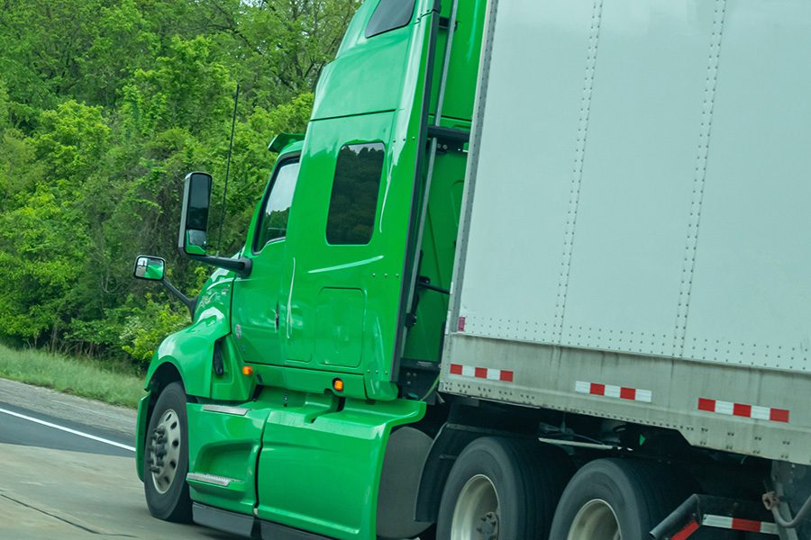 Specialized Business Insurance - Angled View of a Green Truck Pulling a Trailer on the Road